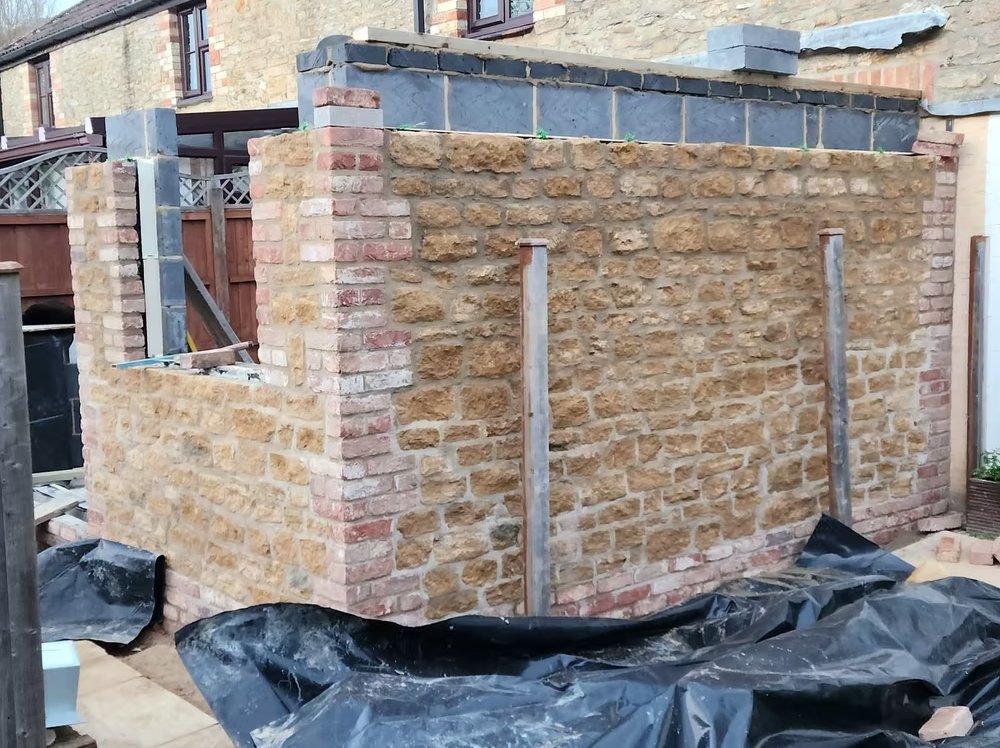 Hamstone outer leaf coursed up around openings